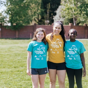 Girls on the Run coach standing besides two program participants outdoors